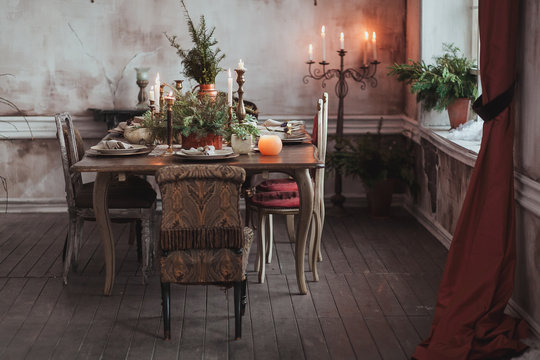 Christmas table setting. Vintage chairs, natural pine tree branches, candles. Rural or rustic style decorations