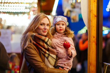 Woman and little girl eating crystalized apple on Christmas mark