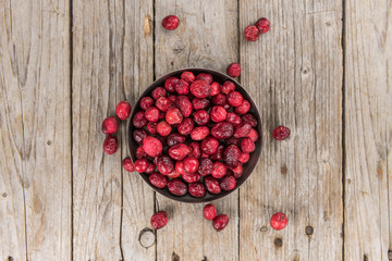 Old wooden table with fresh Dried Cranberries (close-up shot; selective focus)
