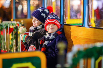 Obraz na płótnie Canvas Two little kids boys on carousel at Christmas market