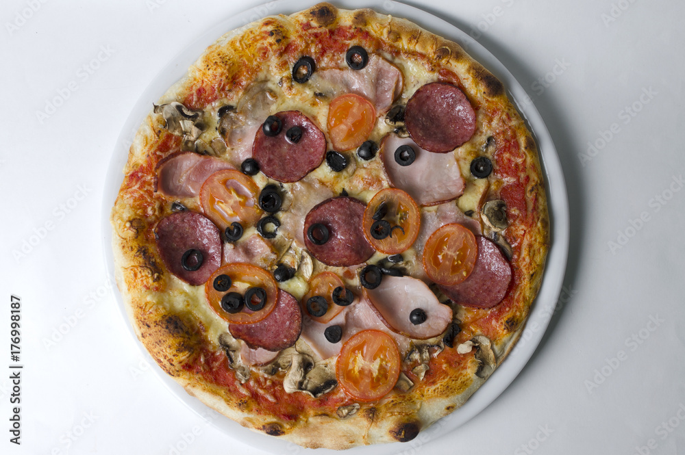 Wall mural Pizza with ham salami and mushrooms on a white plate