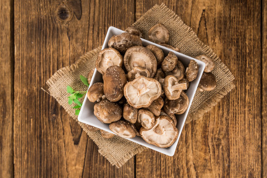 Portion of Raw Shiitake mushrooms on wooden background, selective focus
