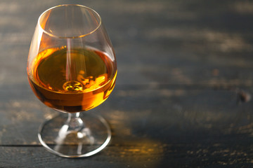 Glass of brandy on black background