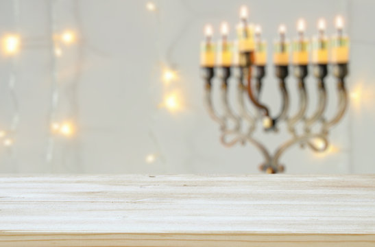 Empty wooden table in front of jewish holiday Hanukkah background with menorah (traditional candelabra)