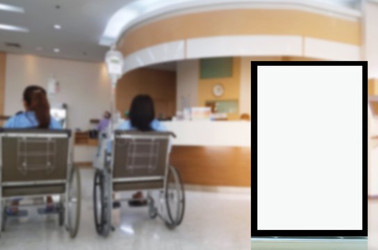 blank advertising billboard or showcase light box with copy space for your text message or media and content with blurred image of patients in wheelchair waiting in lobby at hospital background