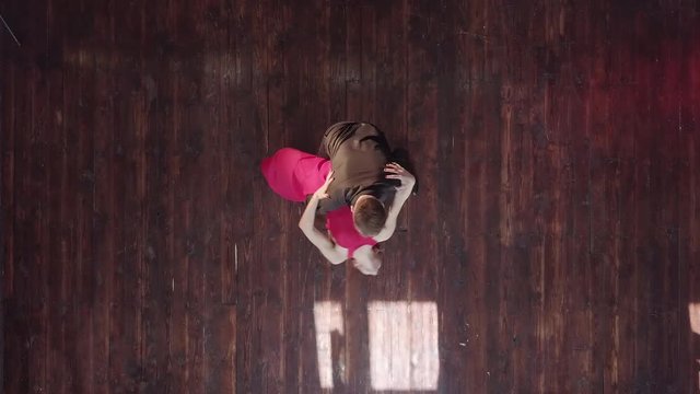 Professional couple dancing tango on the wooden floor in the studio.