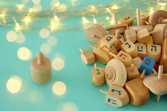 jewish holiday Hanukkah with wooden dreidels colection (spinning top) and gold lights on the table