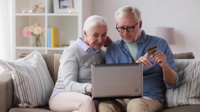 happy senior couple with laptop and credit card