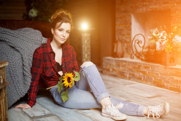 In autumn a beautiful young woman at home with a cozy rug