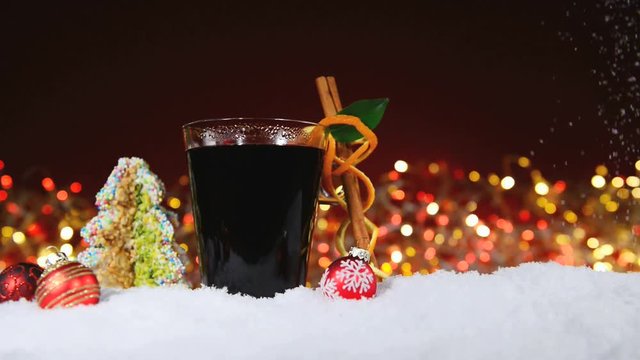 Gl&uuml;hwein mit Weihnachtsgeb&auml;ck im Schnee - Lichterkette im Hintergrund