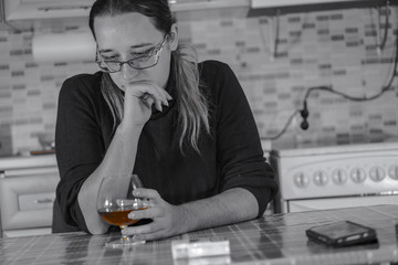 Female alcoholism. Young woman relaxes at home with a glass of drink.