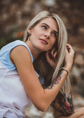 Beautiful blonde woman sitting on a stone embankment and reads book. Hands tattooed. modern, trendy, student. Closeup portrait