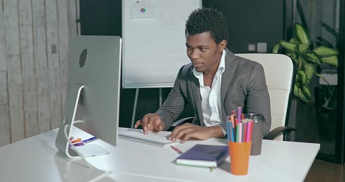 African businessman in the office in front of the computer screen and typing on keyboard