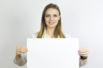 Fototapeta premium Girl with sheet of paper A3. Business girl holding a clean sheet of paper A3. Write your text, advertise your services.