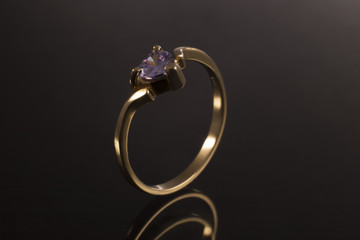 ring in gold with gemstone and diamond, classic jewelry band with gem in background black 