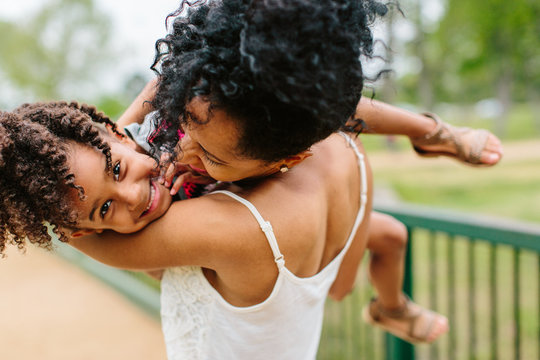 A mother holding her young daughter and giving her kisses.