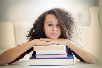 Happy curly hair teen girl resting on books