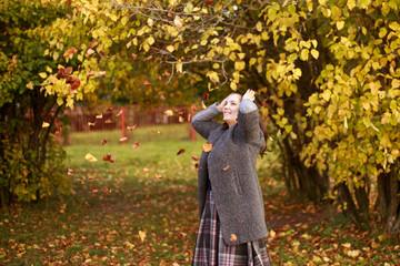 girl in the park throws autumn leaves