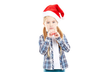 Portrait of sweet little girl in Santa hat blowing into party blower