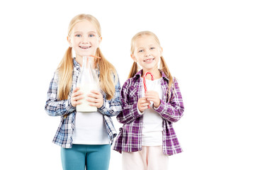 Studio portrait of two little sisters holding bottle of milk and candy cane