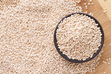 pile of quinoa seeds in container on wood