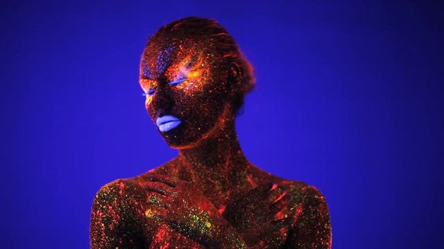 Portrait of beautiful girl with ultraviolet paint in color light