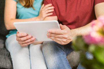 Happy couple using tablet together on couch. Young man and woman browsing internet or watching tv or movie stream online on smart mobile device at home.  © terovesalainen