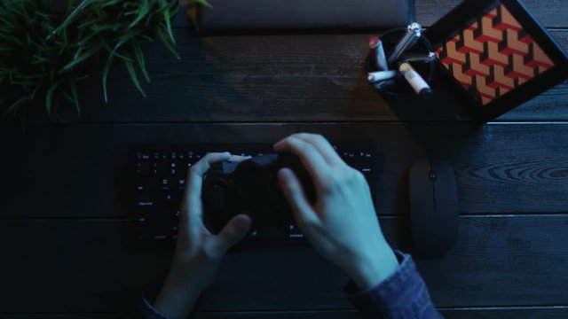 Top down view of man playing games on computer by using joystick