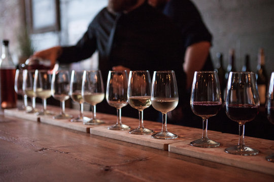 Row of wine glasses being poured with multiple types of wine
