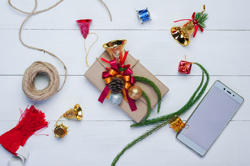 Christmas gift box,rope,cellphone and new year decoration on white wood plate.Flat lay.Christmas and New year concept.