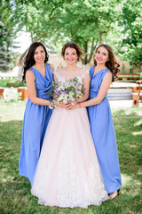 Beautiful bride and bridesmaids in blue dresses pose in the garden