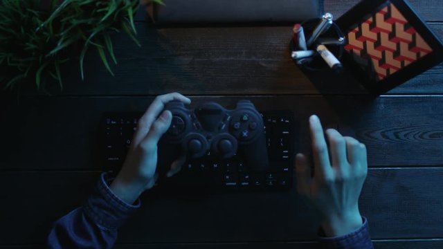 Overhead view of man playing on computer by using gamepad