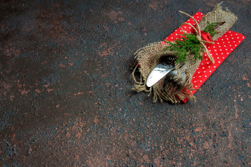 Christmas table setting with fork and knife in sackcloth and spruce branches cones and Christmas decorations on a wooden background with copy space top view flat, holiday concept