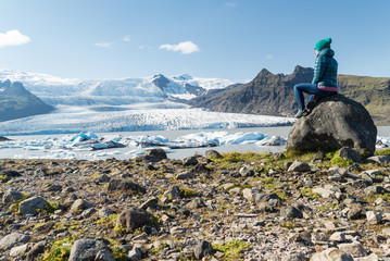 Mujer sentada sobre una piedra a la orilla del lago glaciar Fjallsarlon en Islandia