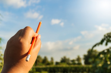 pencil in left hand and blue sky