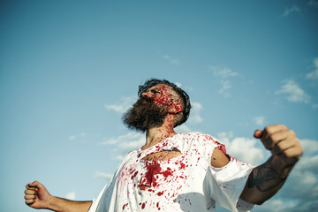 Halloween man bleeding standing with fists hands on blue sky