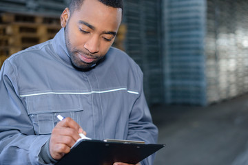 Male worker writing on clipboard