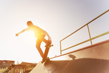 Teen skater hang up over a ramp on a skateboard in a skate park