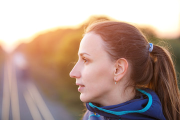 Portrait of young sporty woman on bridge in the evening. Athletic girl standing outdoor after fitness training