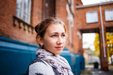 Young female student standing near college building in autumn. Education background with student girl and copy space
