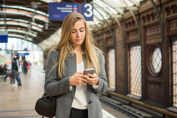 Young woman using phone at train station.
