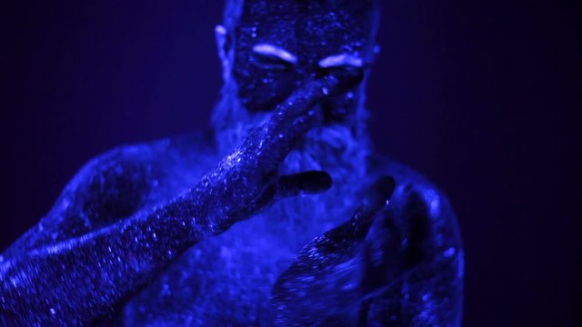 Man painted fluorescent powder dance in ultraviolet light