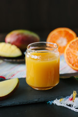 Mango and orange detox drink over black slate board.