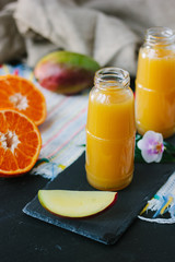 Mango and orange smoothie in transparent bottle.