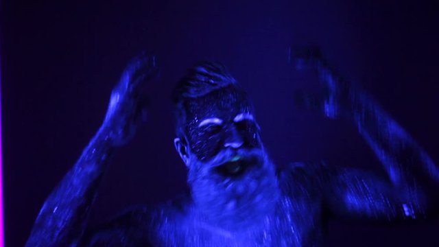 Man painted fluorescent powder dance in ultraviolet light