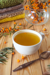 Tea with sea-buckthorn orange berries in a cup. Autumn still life