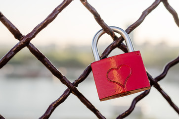 Red padlock with heart symbol on the fence