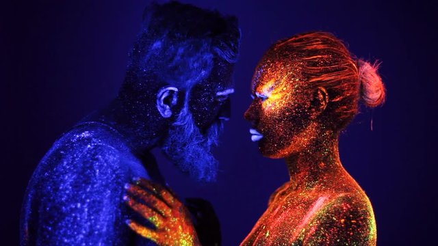 Portrait of a bearded man and woman painted in ultraviolet powder