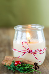 Candle in glass jar with Christmas decorations.