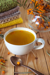 Tea with sea-buckthorn orange berries in a cup. Autumn still life